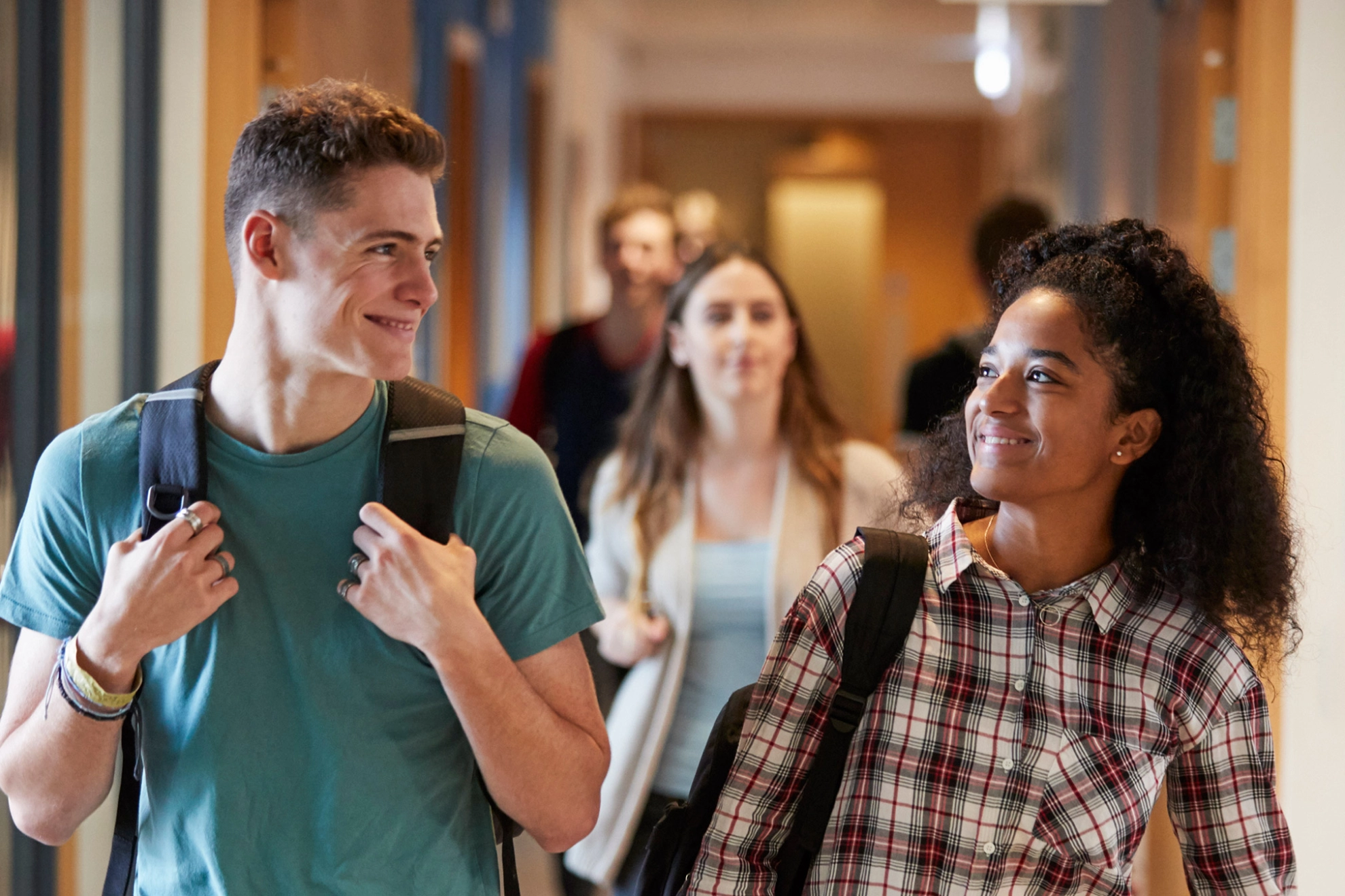 Eine Studentin und ein Student gehen gemeinsam über einen Korridor in einem Universitätsgebäude.
